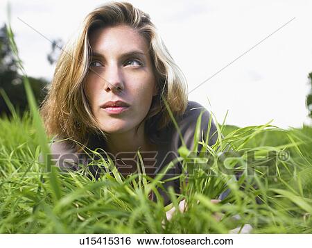 Stock Photograph - Woman laying in a green field portrait.. Fotosearch