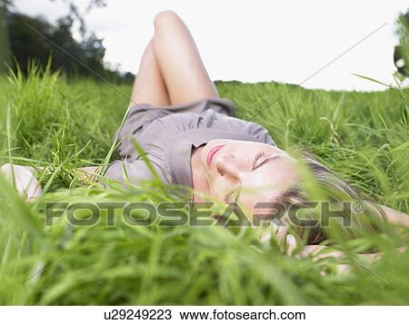 Stock Image - Woman resting in a green field.. Fotosearch