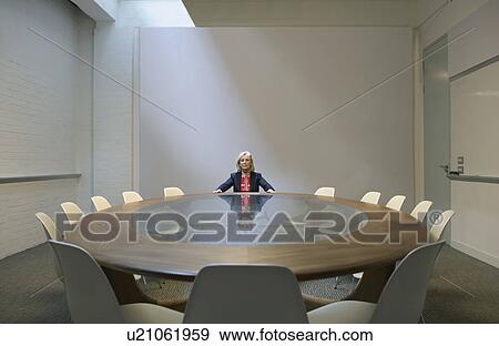 Stock Photo - Woman seated in boardroom alone. Fotosearch