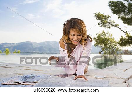 Woman smiling by infinity pool reading newspaper and drinking coffee. View Large Photo Image Stock Image - Woman smiling by infinity pool reading newspaper and drinking coffee.. Fotosearch