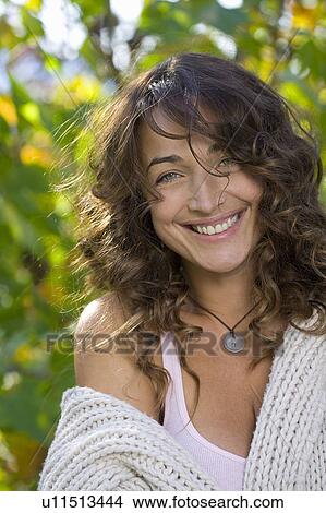 Picture - Woman smiling outdoors looking at camera.. Fotosearch