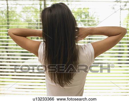 Stock Photograph - Woman standing by a window stretching.. Fotosearch
