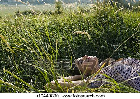 Young woman lying in grass. View Large Photo Image Stock Image - Young woman lying in grass.. Fotosearch