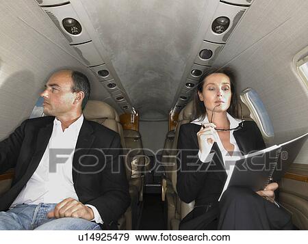 Businesswoman and businessman seated inside a private jet. View Large Photo Image Stock Photo - Businesswoman and businessman seated inside a private jet.. Fotosearch