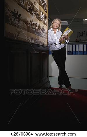 Businesswoman in a hallway with binders View Large Photo Image Picture - Businesswoman in a hallway with binders . Fotosearch