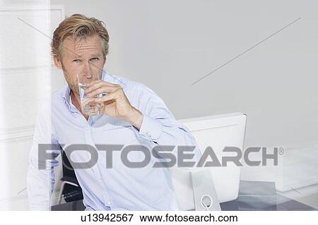 Stock Photo - Man in office drinking water with reflections.. Fotosearch