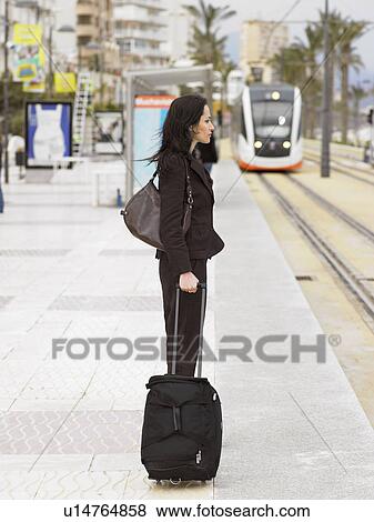 Side view of woman waiting at tram stop with tram in background. Alicante, Spain. View Large Photo Image Stock Photo - Side view of woman waiting at tram stop with tram in background. Alicante, Spain.. Fotosearch