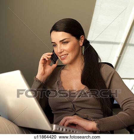 Stock Image - Woman with laptop and phone. Fotosearch