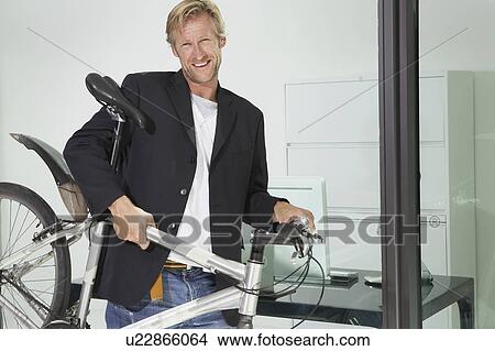 Young businessman in office building with bicycle. View Large Photo Image Picture - Young businessman in office building with bicycle.. Fotosearch