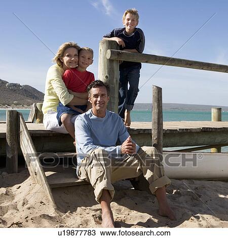 Stock Image - A family sitting on a beach. Fotosearch