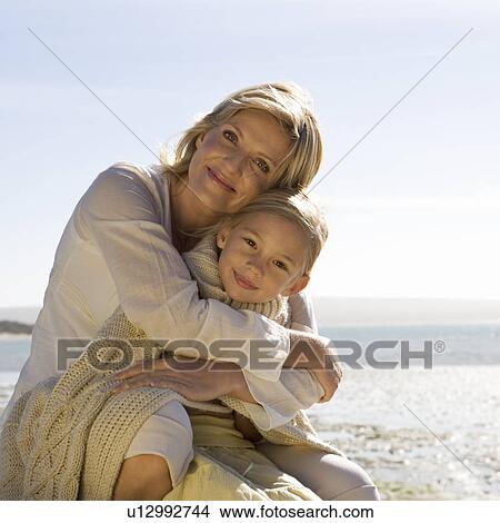 Picture - A mother and daughter sitting on a beach. Fotosearch