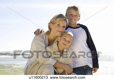 Stock Image - A mother and her children sitting on a beach. Fotosearch
