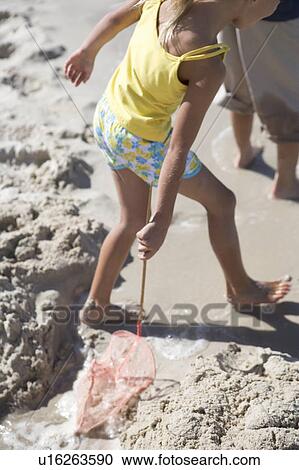 Stock Image - A young girl playing on a beach. Fotosearch