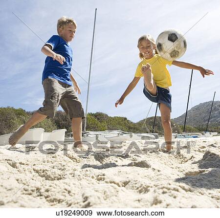 Stock Photo - Two children playing football on a beach. Fotosearch