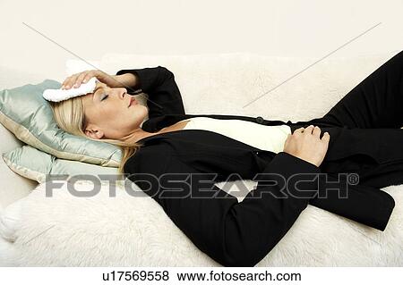 Business woman laying on the sofa with a headache View Large Photo Image Stock Photo - Business woman laying on the sofa with a headache. Fotosearch