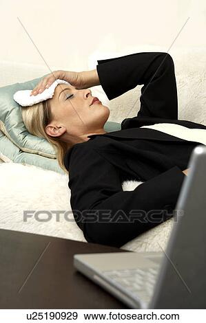 Business woman laying on the sofa with a headache View Large Photo Image Stock Photo - Business woman laying on the sofa with a headache. Fotosearch
