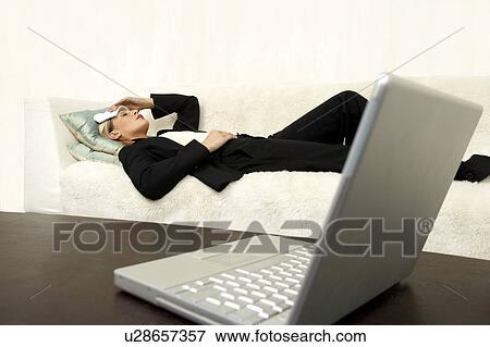 Business woman laying on the sofa with a headache View Large Photo Image Stock Photo - Business woman laying on the sofa with a headache. Fotosearch