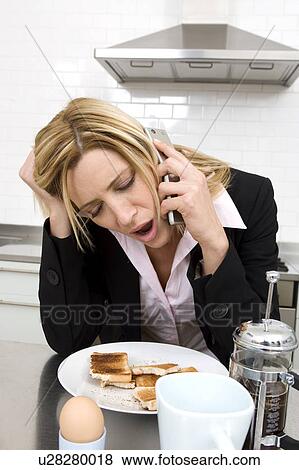 Businesswoman having breakfast in the kitchen and talking on the phone View Large Photo Image Stock Photo - Businesswoman having breakfast in the kitchen and talking on the phone. Fotosearch