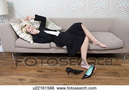 Businesswoman laying on a sofa talking on the phone View Large Photo Image Stock Photo - Businesswoman laying on a sofa talking on the phone. Fotosearch