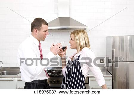 Stock Photo - Couple drinking wine in the kitchen. Fotosearch