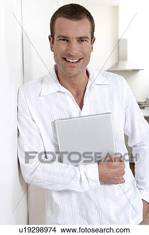Picture - Young man holding a laptop. Fotosearch