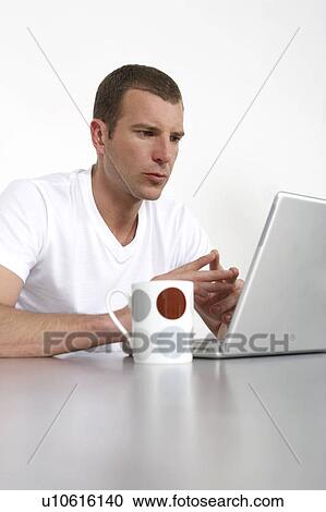Young man working on a laptop View Large Photo Image Stock Image - Young man working on a laptop. Fotosearch