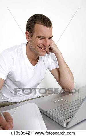 Young man working on a laptop View Large Photo Image Stock Photo - Young man working on a laptop. Fotosearch