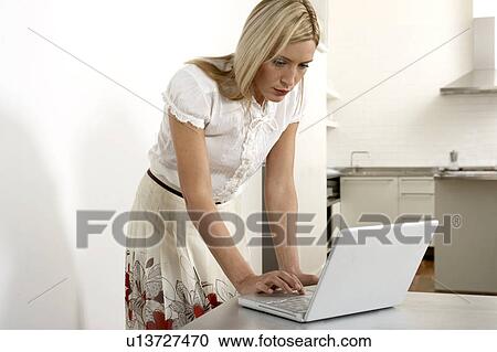 Stock Image - Young woman working from home. Fotosearch