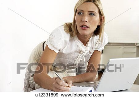 Stock Photo - Young woman working from home. Fotosearch