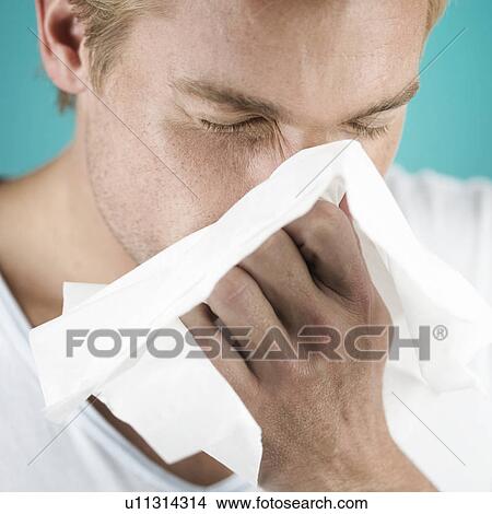 A young man blowing his nose View Large Photo Image Picture - A young man blowing his nose. Fotosearch