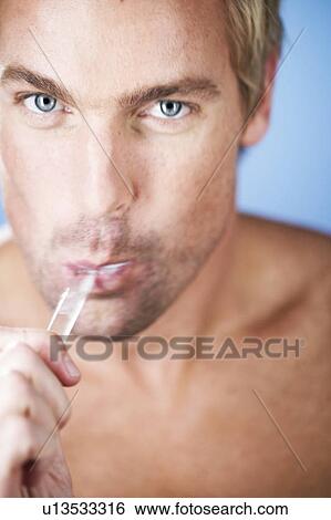 Stock Photograph - A young man brushing his teeth. Fotosearch