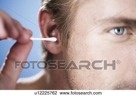 Stock Image - A young man cleaning his ear. Fotosearch