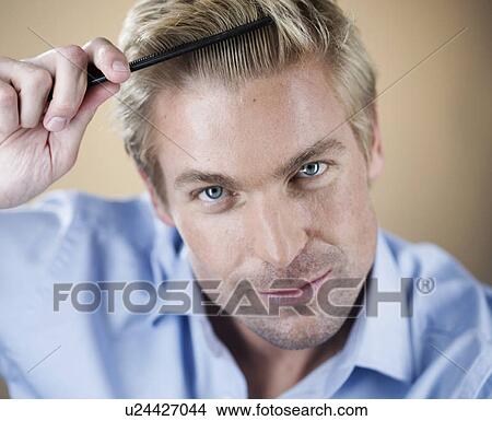 Picture - A young man combing his hair. Fotosearch