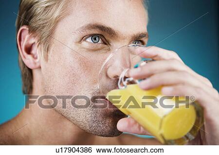 Stock Photograph - A young man drinking a glass of orange juice. Fotosearch