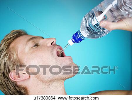 Picture - A young man drinking water from a bottle. Fotosearch