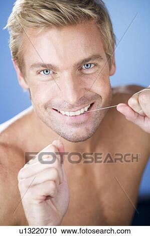 Stock Image - A young man flossing his teeth. Fotosearch