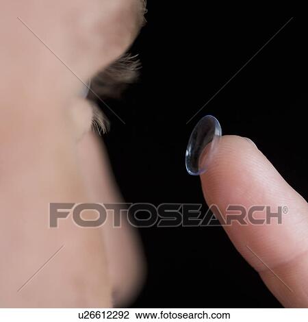 Stock Image - A young man inserting a contact lens. Fotosearch