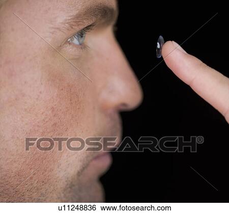 A young man inserting a contact lens View Large Photo Image Stock Photograph - A young man inserting a contact lens. Fotosearch