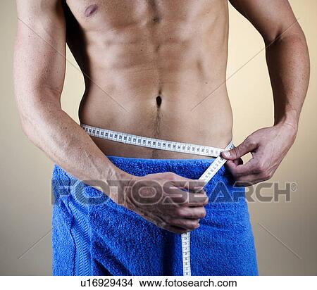 Picture - A young man measuring his waist. Fotosearch