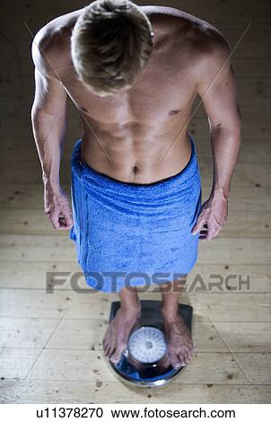 A young man standing on scales View Large Photo Image Stock Image - A young man standing on scales. Fotosearch