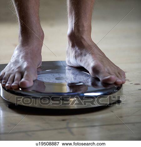 A young man standing on scales View Large Photo Image Stock Photo - A young man standing on scales. Fotosearch