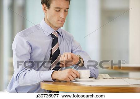 Stock Photo - A businessman checking the time on his watch. Fotosearch