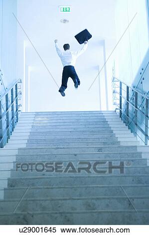 Stock Photography - A businessman jumping at the top of stairs. Fotosearch