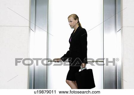 Stock Image - A businesswoman standing in a lift. Fotosearch