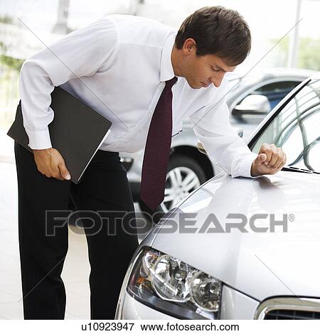 Stock Photo - A car salesman polishing a car. Fotosearch