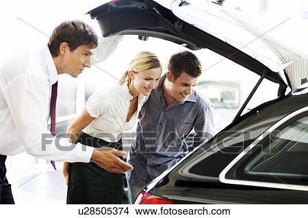Picture - A young couple admiring a new car. Fotosearch