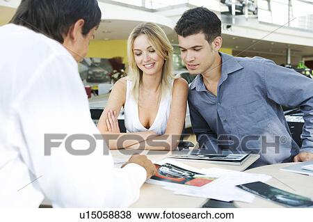 Stock Photo - A young couple buying a new car. Fotosearch