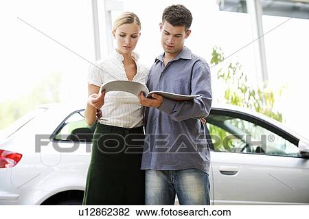 Stock Image - A young couple looking through a car brochure. Fotosearch