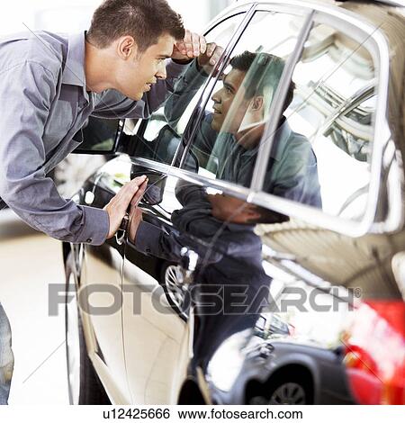 Stock Photograph - A young man admiring a new car. Fotosearch