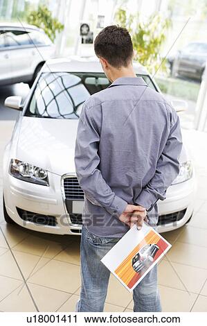 A young man looking at a new car View Large Photo Image Stock Image - A young man looking at a new car. Fotosearch